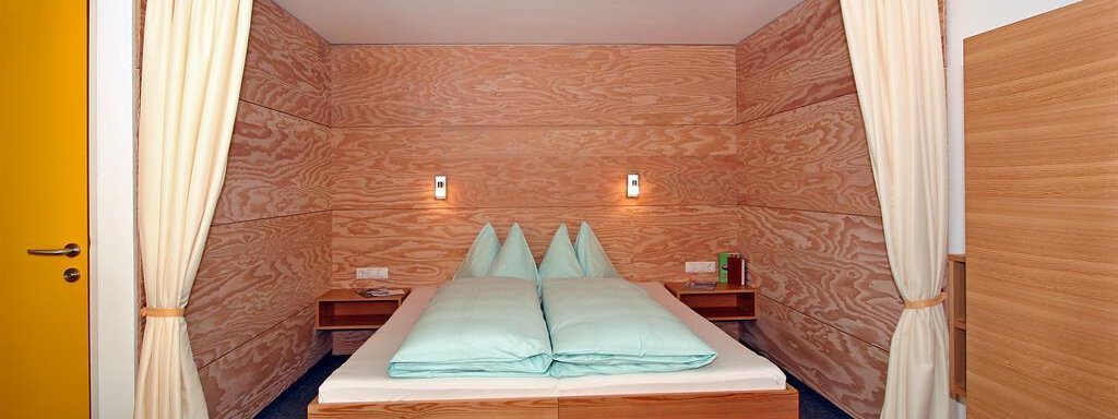 A modern bedroom with wood paneling and two beds. The soft colors and spacious design create a cozy atmosphere. - Ferienwohnungen Broser - Obergurgl 