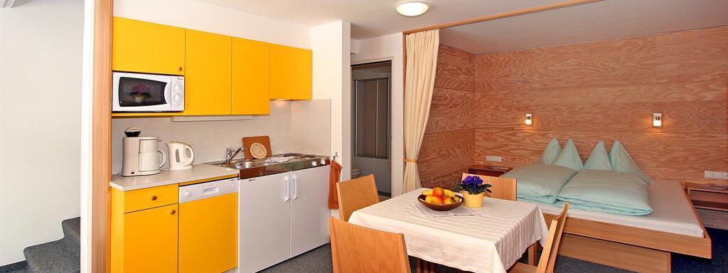 A bright apartment with modern furniture. The kitchen is yellow and well-equipped, the sleeping area has a cozy double bed. - Ferienwohnungen Broser - Obergurgl 