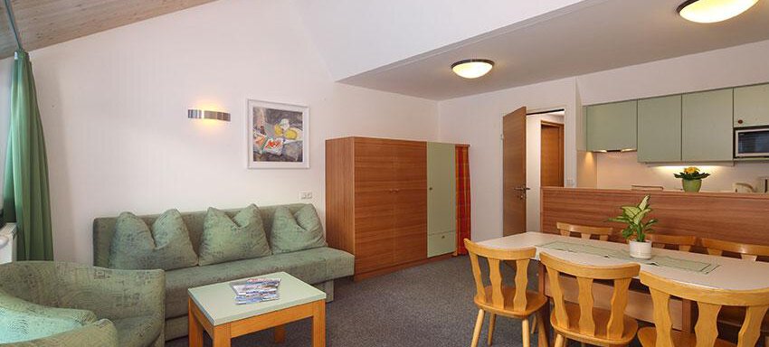 A cozy living area with a sofa and a dining table. The kitchen is modern and well-equipped. - Ferienwohnungen Broser - Obergurgl 