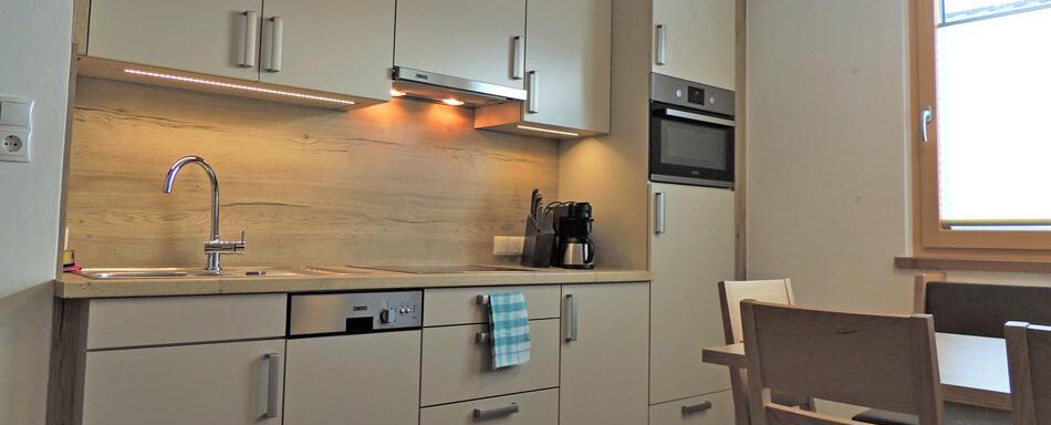 A modern kitchen with light cabinets and a practical layout. The dining area is cozy and inviting. - Haus Christophorus - Obergurgl 