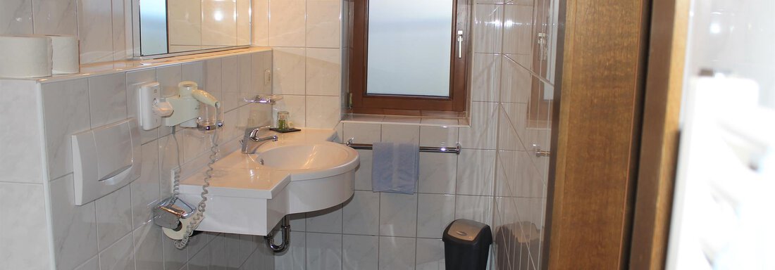 A modern bathroom with bright tiles and a window. The amenities include a sink, a toilet, and towels. - Haus Martinshof - Obergurgl 