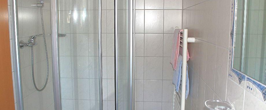 A modern bathroom with a shower and bright tiles. Towels hang on a towel rack. - Haus Martinshof - Obergurgl 