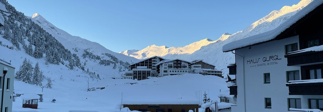 A snowy landscape with mountains in the background and a clear blue sky. In the foreground, modern buildings and a snow-covered environment can be seen. - Haus Verwall Appartements - Obergurgl 