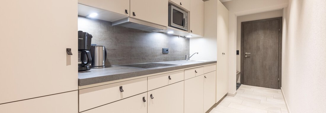 A modern kitchen with bright furniture and good lighting. It includes a microwave, a coffee machine, and ample storage space. - Haus Verwall Appartements - Obergurgl 