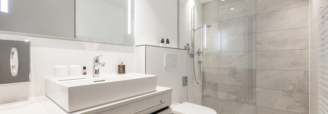 A modern bathroom with bright tiles and a spacious shower. The wash area is functional and stylishly furnished. - Haus Verwall Appartements - Obergurgl 