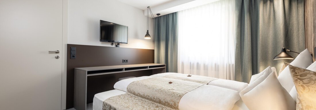A modern hotel room with two beds and a cozy atmosphere. Large windows provide plenty of daylight and a pleasant ambiance. - Haus Verwall Appartements - Obergurgl 
