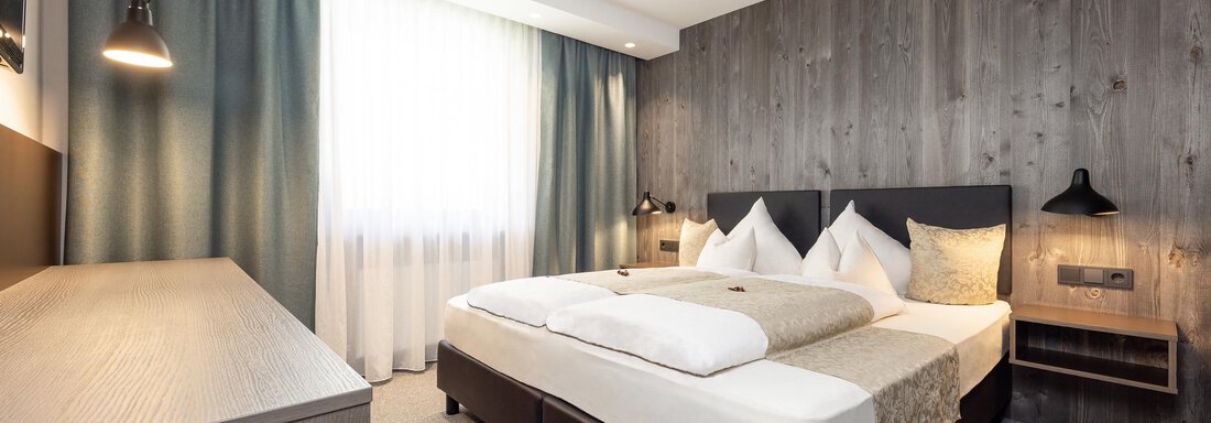 A modern bedroom with a large bed and stylish furniture. The walls are painted in neutral tones and the lighting is soft. - Haus Verwall Appartements - Obergurgl 