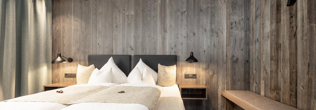 A modern bedroom with wood paneling and a comfortable double bed. The soft lighting creates a cozy atmosphere. - Haus Verwall Appartements - Obergurgl 