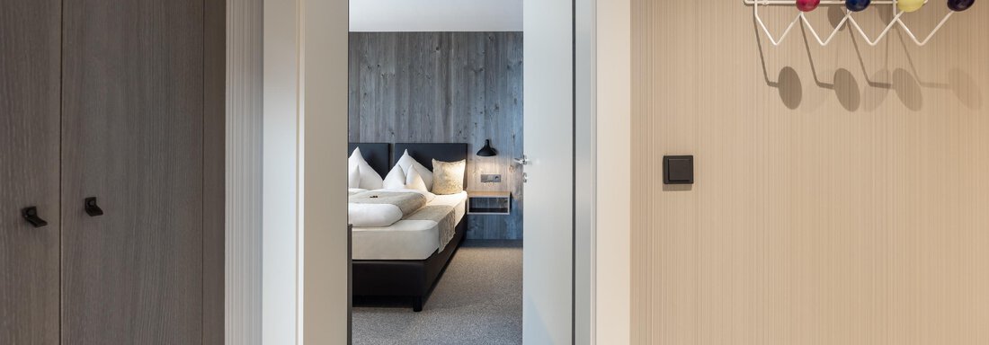 A modern hallway with access to a bedroom. A colorful coat hook hangs on the wall. - Haus Verwall Appartements - Obergurgl 