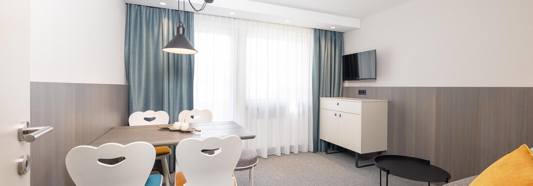 A modern living room with a dining area and a cozy couch. The room design is bright and inviting. - Haus Verwall Appartements - Obergurgl 