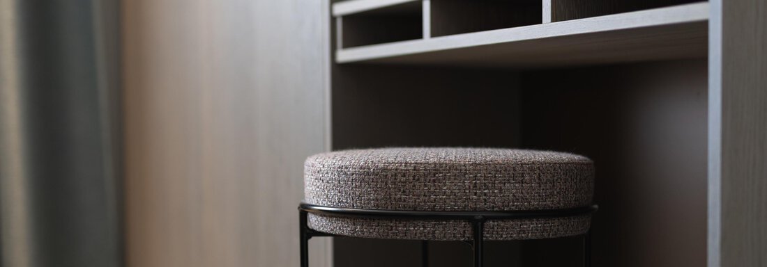 A modern workplace with a wooden table and a padded stool. The environment feels minimalist and inviting. - Haus Verwall Appartements - Obergurgl 