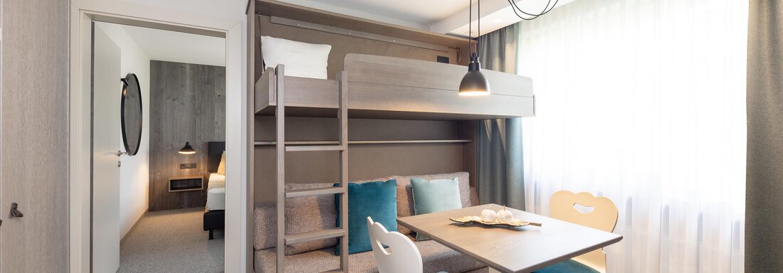 A modern room with a loft bed and a table. The room is bright and comfortably designed. - Haus Verwall Appartements - Obergurgl 