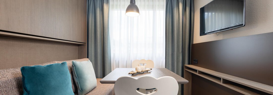 A modern living room with a cozy seating area and a table.  
Large windows let in plenty of daylight and create a bright atmosphere. - Haus Verwall Appartements - Obergurgl 