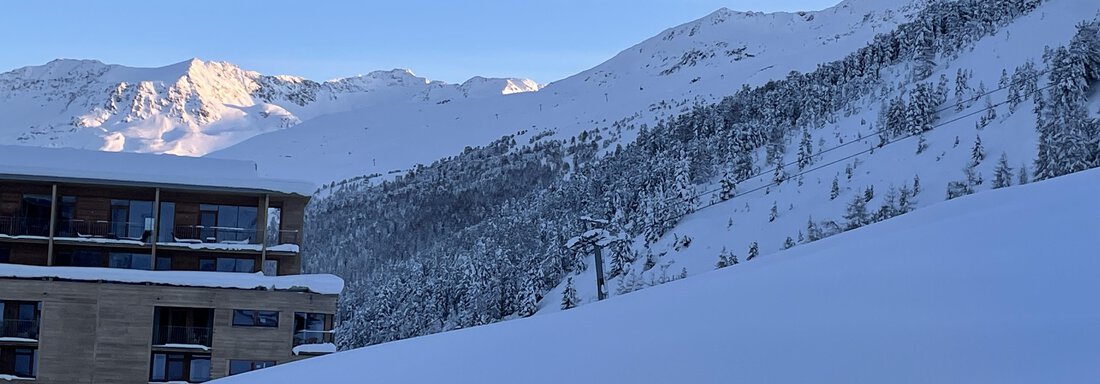 A snow-covered landscape with mountains in the background. In the foreground, a modern building can be seen. - Haus Verwall Appartements - Obergurgl 