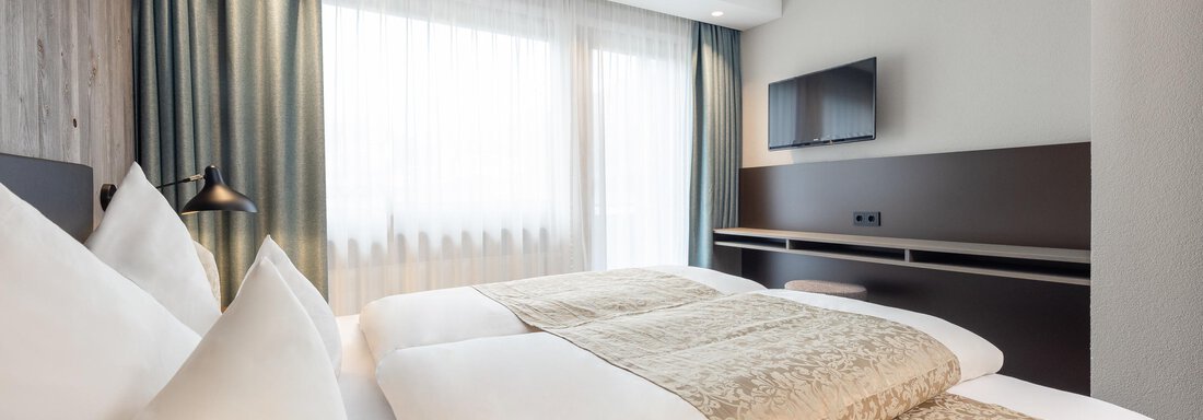 A modern hotel room with two beds and large windows. The decor is bright and comfortable. - Haus Verwall Appartements - Obergurgl 