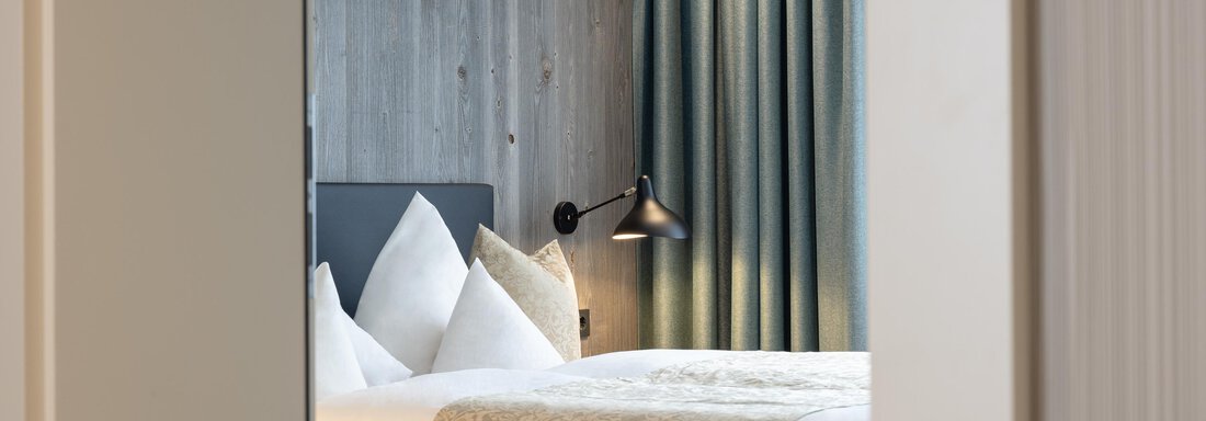 A stylish bedroom with a comfortable bed and elegant pillows. The warm colors and soft light create a cozy atmosphere. - Haus Verwall Appartements - Obergurgl 