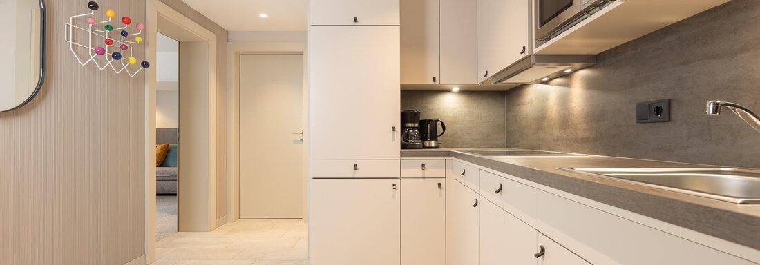 A modern kitchen with bright cabinets and a stone countertop. The environment is well-lit and appears inviting. - Haus Verwall Appartements - Obergurgl 