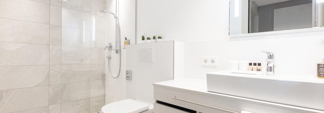 A modern bathroom with a walk-in shower and an elegant sink. The walls are light and the furnishings are simple and functional. - Haus Verwall Appartements - Obergurgl 
