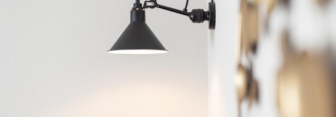 A modern wall lamp in black design. It is mounted on a light wall and illuminates the room. - Haus Verwall Appartements - Obergurgl 