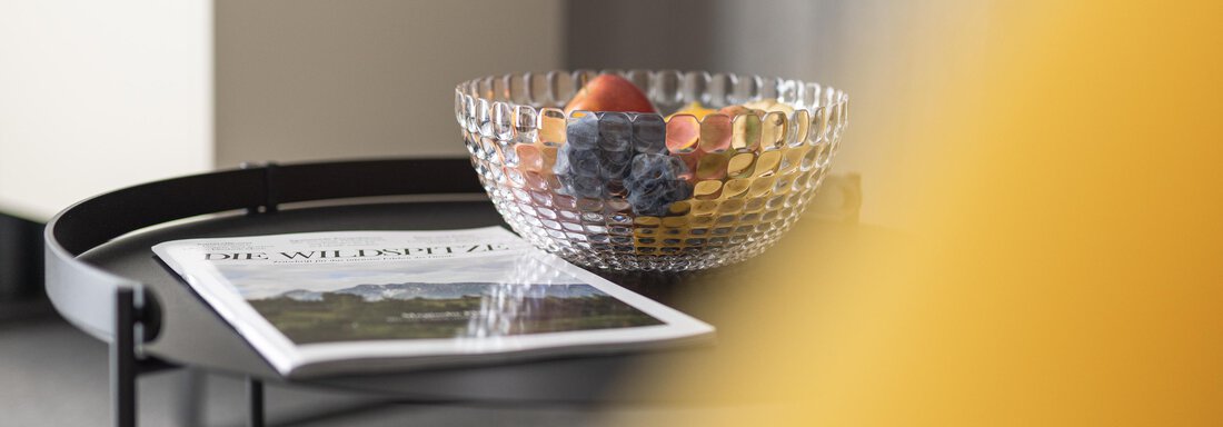 A stylish glass bowl with fruit is on a table. Next to it lies a magazine. - Haus Verwall Appartements - Obergurgl 