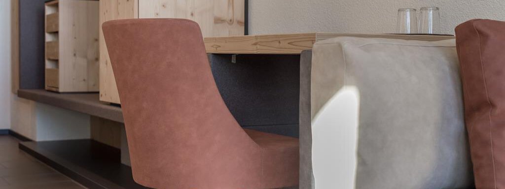 A modern room with a wooden table and a brown chair. In the background, shelves and a gray couch are visible. - Hotel-Garni Pirchhütt - Obergurgl 