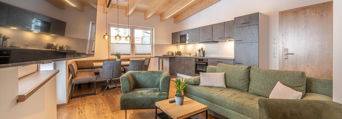 A modern apartment with an open living kitchen. Light green sofas and a wooden table create a cozy atmosphere. - Mein Gaisberg - Obergurgl 