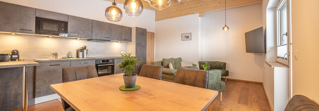 Modern kitchen with a large wooden dining table. Cozy seating and warm light create an inviting atmosphere. - Mein Gaisberg - Obergurgl 