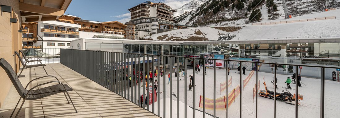A view from a balcony of an ice rink, surrounded by snowy mountains. There are people skating, and a clear, sunny sky. - Mein Gaisberg - Obergurgl 