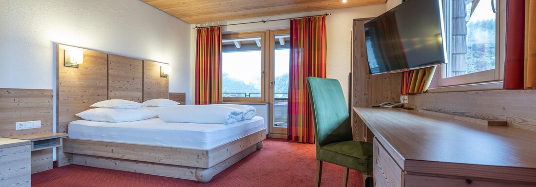 Doppelzimmer Typ A A modern hotel room with a double bed and a small table. Large windows provide plenty of daylight and a view outside. - Schönblick Gurgl - Obergurgl