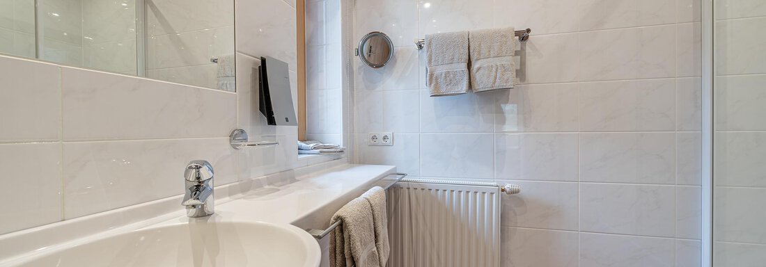 A modern bathroom with a round sink and large tiles. There is a shower area and some towels are hanging decoratively. - Schönblick Gurgl - Obergurgl 