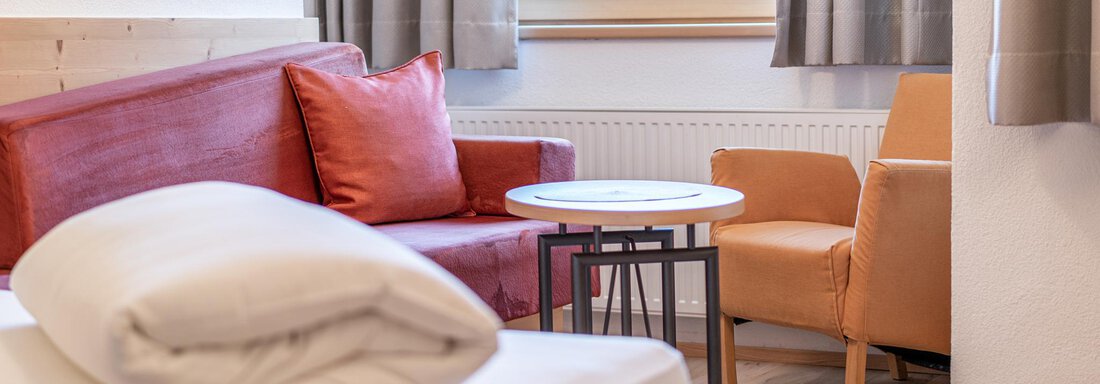 A cozy living room with a red sofa and a light chair. Large window with curtains that lets in daylight. - Schönblick Gurgl - Obergurgl 