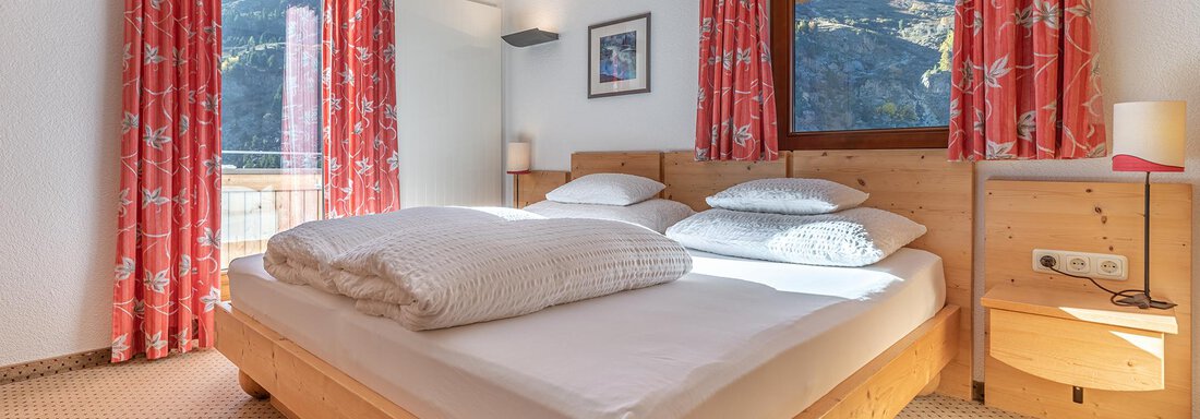 A cozy bedroom with a double bed and colorful curtains. Large windows offer a view of the mountains. - Schönblick Gurgl - Obergurgl 