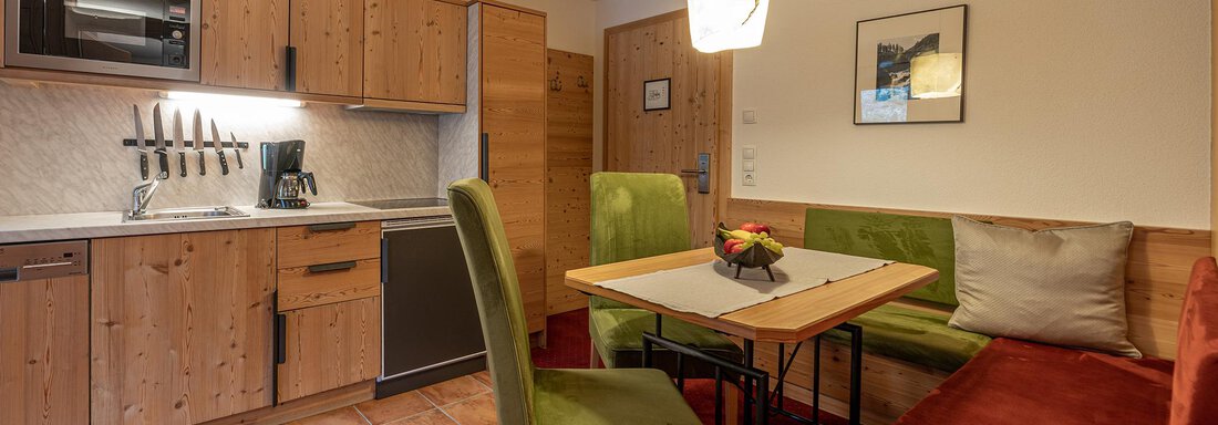 Küche Appartement "5+7" A cozy kitchen with wooden cabinets and a dining area. The room is bright and cheerfully furnished. - Schönblick Gurgl - Obergurgl
