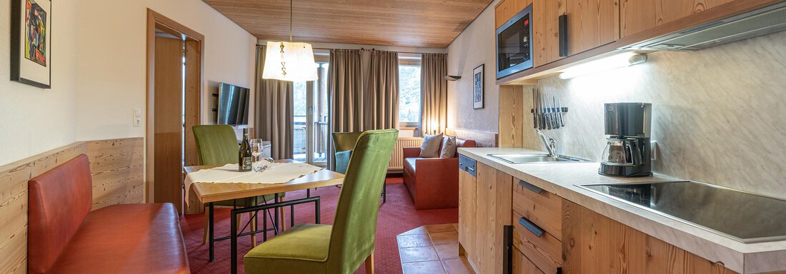A cozy apartment with a modern kitchen and a dining area. The room is bright and inviting with wooden paneling and colorful furniture. - Schönblick Gurgl - Obergurgl 