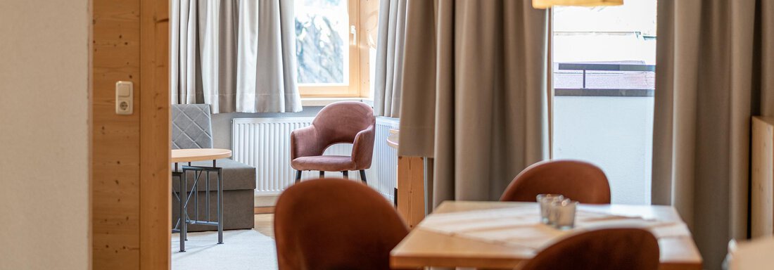 A cozy living area with a dining table and elegant chairs. Large windows provide plenty of daylight and a view of the quiet surroundings. - Schönblick Gurgl - Obergurgl 