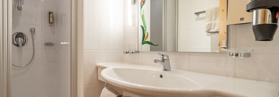 A modern bathroom with a shower and sink. The walls are brightly tiled and there are fresh towels as well as a mirror. - Schönblick Gurgl - Obergurgl 
