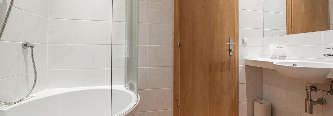 A modern bathroom with a shower and a bathtub. The floor is tiled in brown and there is a wood stove in the room. - Schönblick Gurgl - Obergurgl 