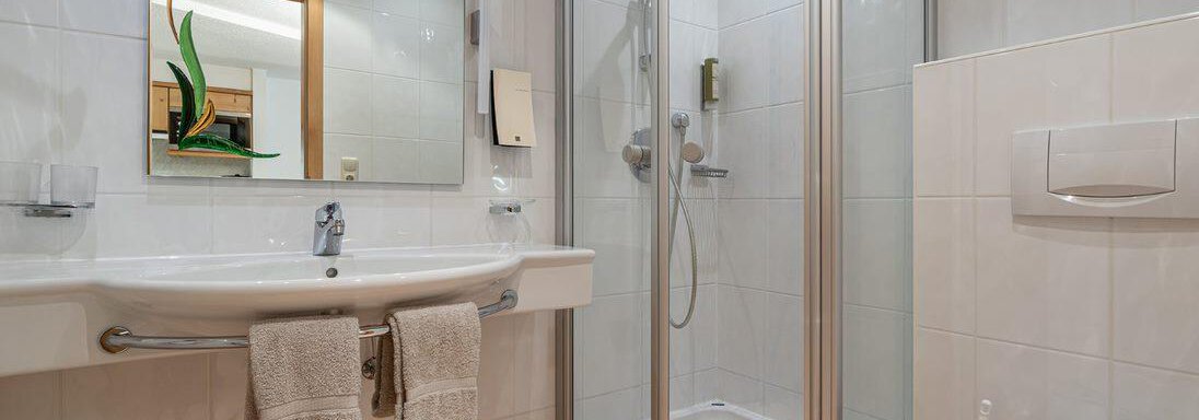 A modern bathroom with a shower and a sink line. The walls are brightly tiled, and the lighting creates a pleasant atmosphere. - Schönblick Gurgl - Obergurgl 