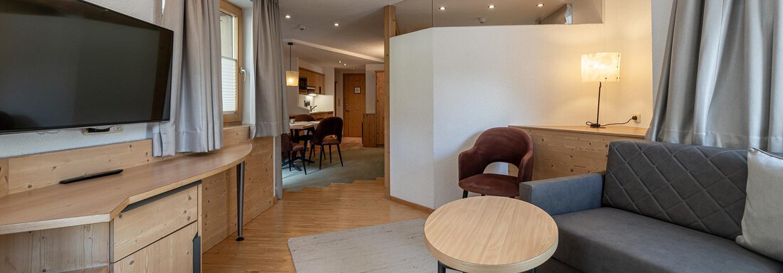 A modern living room with wooden details and a large television. There is a comfortable sofa, a round table, and an inviting atmosphere. - Schönblick Gurgl - Obergurgl 
