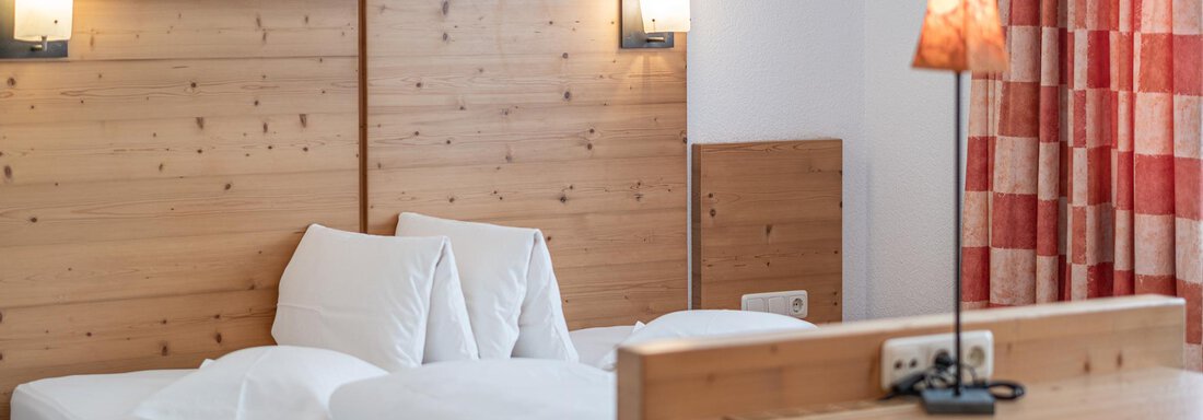 A cozy bedroom with a large bed and light wood design. The windows are decorated with red patterned curtains. - Schönblick Gurgl - Obergurgl 