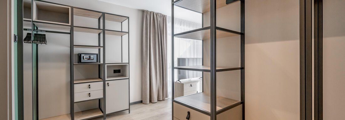 A modern room with open shelves and a minimalist design. Large windows provide plenty of natural light. - The Moss - Your unique hideaway - Obergurgl 