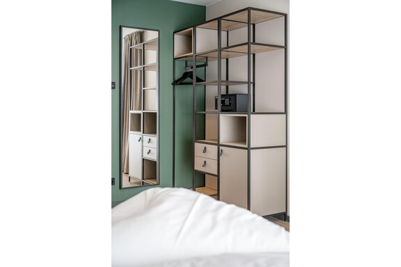 A modern room with an open wardrobe and a large mirror. The walls are green, and the furniture has an elegant, simple structure. - The Moss - Your unique hideaway - Obergurgl 