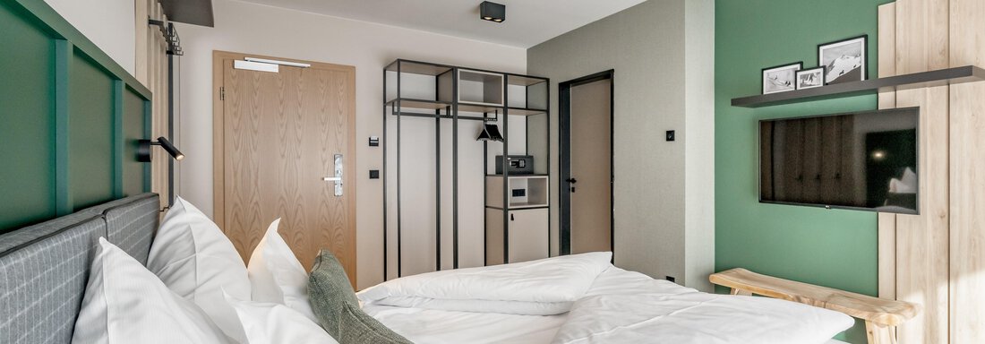 Zimmer A modern bedroom with a large bed and bright decor. The walls are painted in calming colors and there is a television as well as practical furniture. - The Moss - Your unique hideaway - Obergurgl