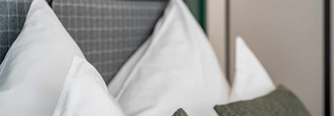 An elegant headboard with white pillows and green decorative cushions. The atmosphere is modern and cozy. - The Moss - Your unique hideaway - Obergurgl 