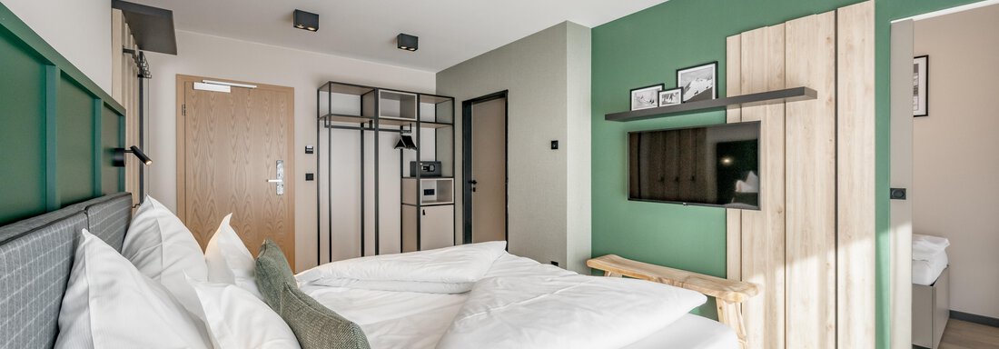 Room interior A modern hotel room with a large bed and artistic accents. The walls are painted in calming colors, and there is plenty of natural light. - The Moss - Your unique hideaway - Obergurgl