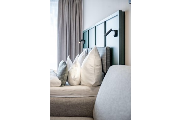 A modern bedroom with a cozy bed and many pillows. The room has large windows and a relaxing atmosphere. - The Moss - Your unique hideaway - Obergurgl 
