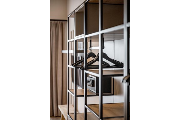 A modern wardrobe with black hangers and an elegant design. In the background, curtains and a stylish room design can be seen. - The Moss - Your unique hideaway - Obergurgl 