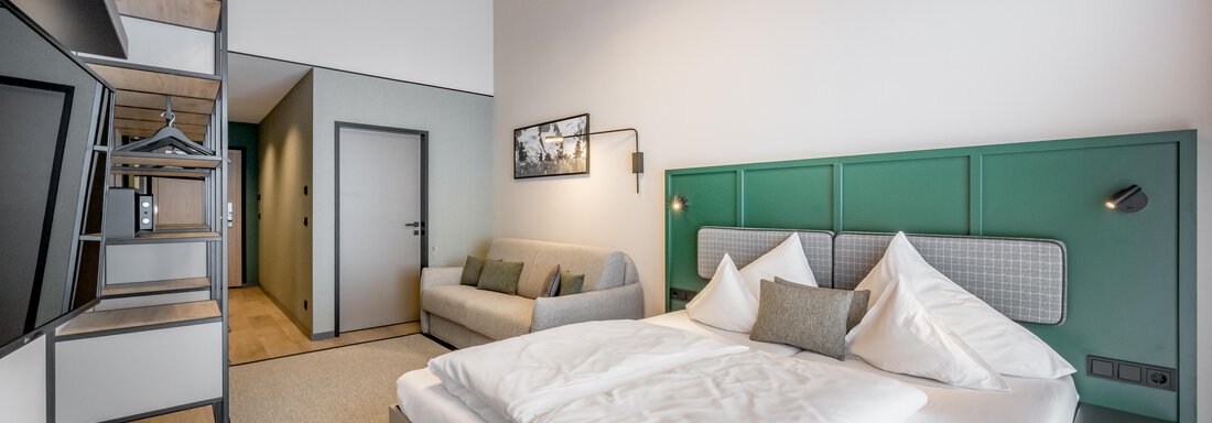 Room interior A modern room with a large, comfortable bed and stylish furniture. The walls are painted in soft shades of green, and the atmosphere feels welcoming and bright. - The Moss - Your unique hideaway - Obergurgl