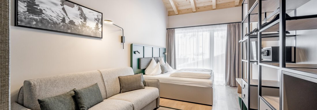 A modern room with a comfortable sofa and a double bed.  
Large windows let in plenty of daylight. - The Moss - Your unique hideaway - Obergurgl 