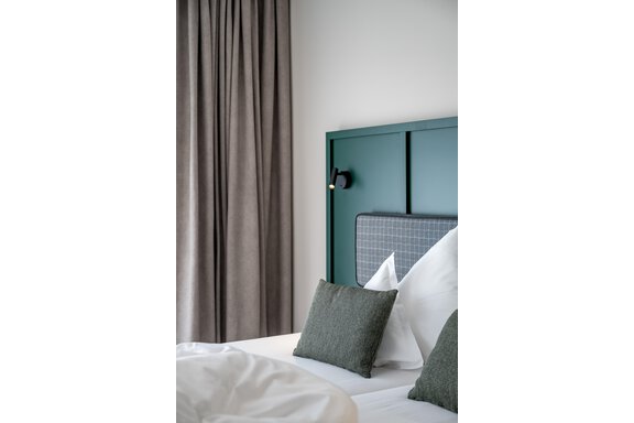 A modern bedroom with a green headboard and soft pillows. Long, gray curtains hang in front of the window. - The Moss - Your unique hideaway - Obergurgl 